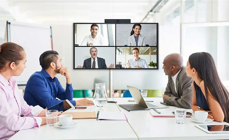 Représentation du métier Visioconférence avec une image de Salle de visioconférence avec un groupe de personne en présentiel et d'autres en distanciel